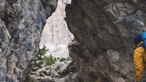 Young man hiker hiking under mountain narrow passage. Yellow jacket, backpack Video stock 122000997