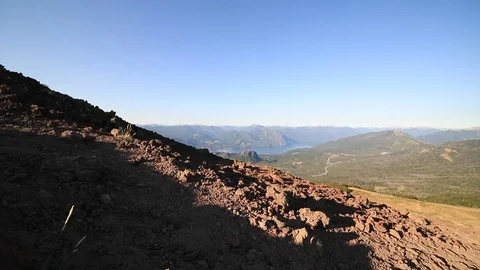 Young man hiking bare soil mountain slope. Wide natural landscape at background Видео 126729170