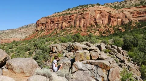 Young man hiking through a red rocked canyon in Colorado. Stock Footage 54076791