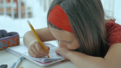 Young man with his head on the table writes homework 스톡 동영상 130478965