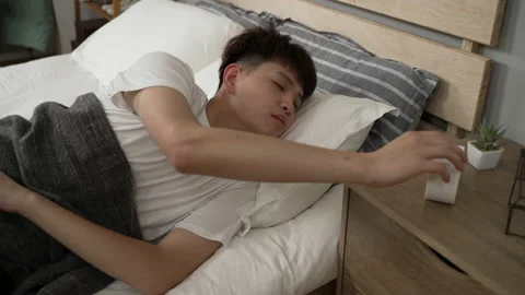 Young man hitting the snooze button on the alarm Stock Footage 162955192