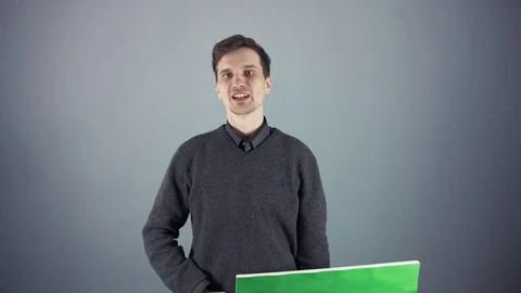 Young man holding a blank poster on gray background Stock Footage 69916632