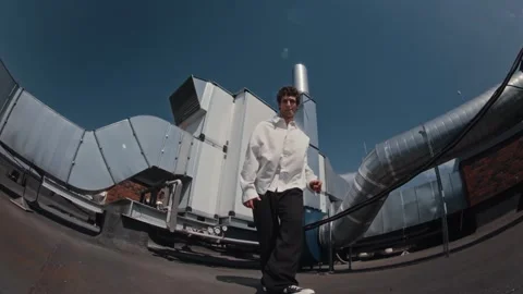 Young man holding breakdance freeze on industrial rooftop beside silver ducts Stock Footage 345248565