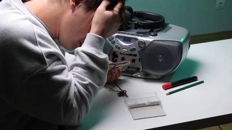 Young man holding a broken audio cassette tape with tangled magnetic film Stock Footage 345170328