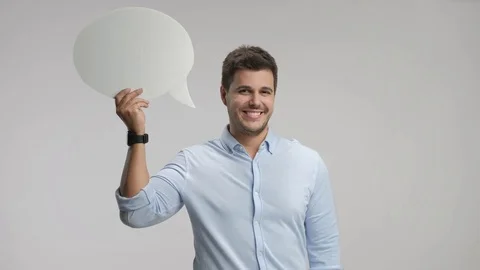 Young man holding a chat bubble and smiling 스톡 동영상 77790024