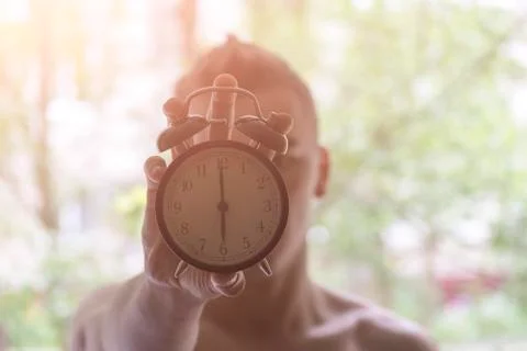 A young man holding a clock. The concept of active in the morning. Awakening. Stock Photos