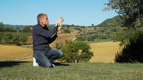 Young Man Holding Ginger Kitten in Hands Outdoors Stock Footage 121301940