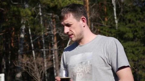 A young man is holding a glass in the hands of a green forest . 4k, 3840x2160 Stock Footage