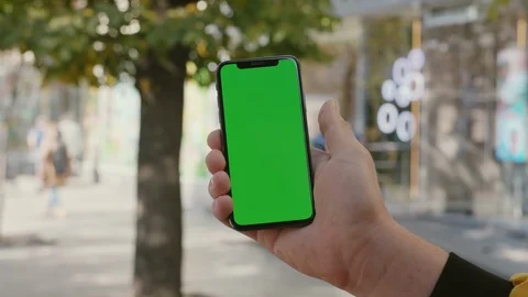 Young man holding in hand vertical smartphone and browsing on blank chrome key Video stock 117428610