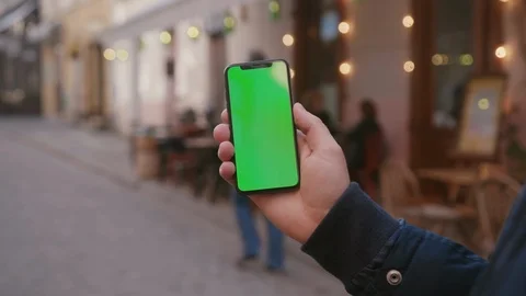 Young man holding handheld vertical smartphone with mock-up chroma key green Stock Footage 117428240