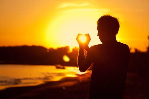 Young man holding in hands the setting sun Stock Photos