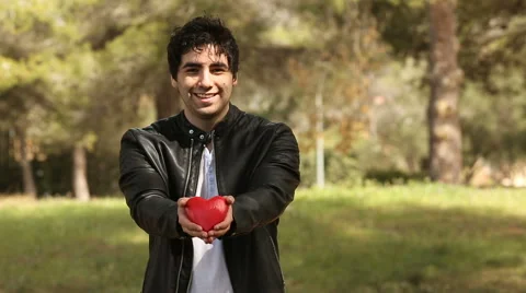 Young man holding heart shape in the park Stock Footage 61860496