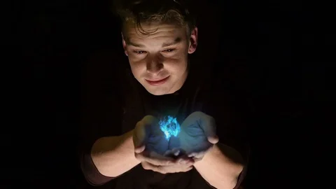 Young man holding a hovering blue flame in his hands. Stock Footage 110315596