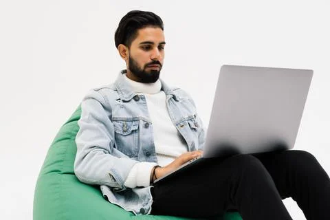 Young man holding notebook browsing chatting colleagues sitting comfy soft ar Stock Photos