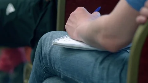 Young man holding a notebook on his lap and listening to a lecture Stock Footage 76244217