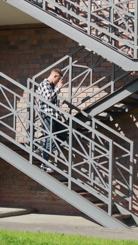 Young man holding object while ascending descending geometric metal staircase Stock Footage 347696491