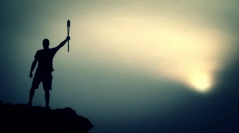 Young man holding the Olympic torch standing on the top of the city at sunset.  Video stock 62960716