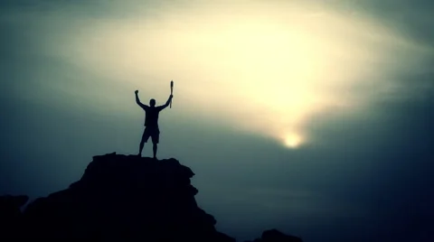 Young man holding the Olympic torch standing on the top of the city at sunset.  Видео 62961919