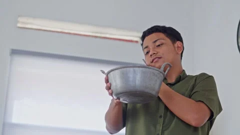 Young Man holding pot to catch water from leaking ceiling while on phone Stock Footage 331326103