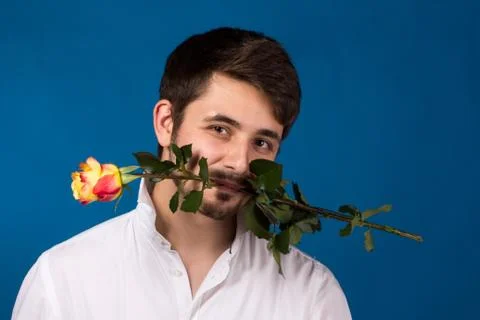 Young man holding a red rose in his mouth Fotos de archivo