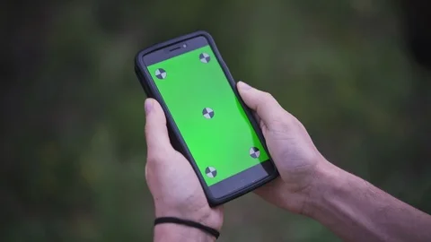 Young Man Holding Smartphone with empty green screen, outdoors Stock Footage 89984753