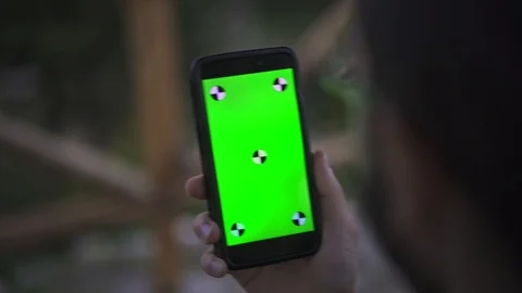 Young Man Holding Smartphone with empty green screen, outdoors Видео 89984787