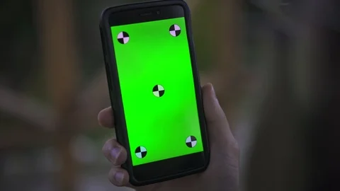 Young Man Holding Smartphone with empty green screen, outdoors Stockbeeldmateriaal 89984792