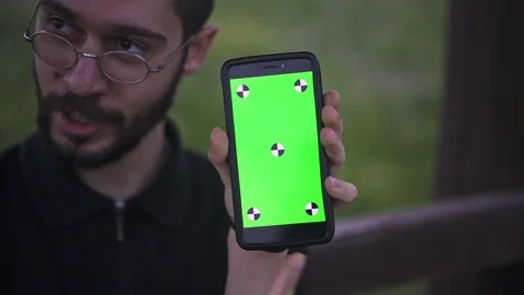Young Man Holding Smartphone with empty green screen, outdoors Stock Footage 89984835