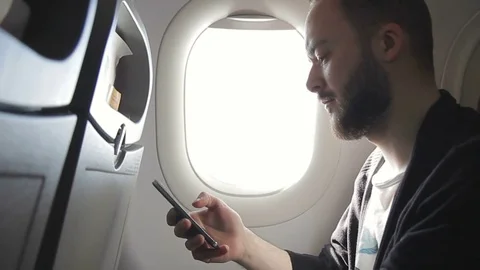 Young man is holding smartphone while sitting in plane indoors. Stock Footage 83122352