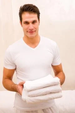 Young man holding stack of fresh towels Stock Photos