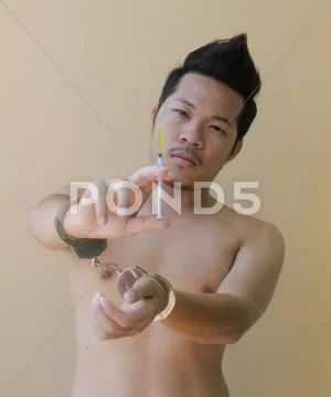 Young man holding syring in hand with handcuffs Stock Photos