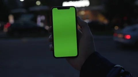Young man holding use smartphone with vertical green screen on night city light Stock Footage 111597003