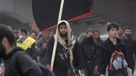 Young man holds big flag while walking in Arbaeen pilgrimage in Karbala, Iraq Stock Footage 119225534