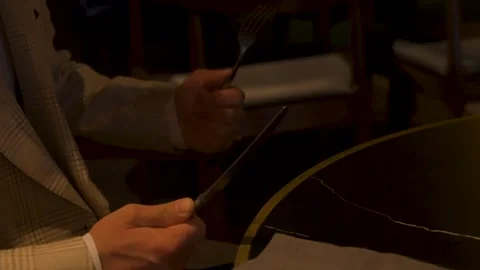 A young man holds cutlery while sitting at a table Vidéo 348011039