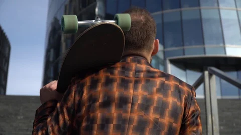 The young man holds a longboard in his hands behind his back, Stock Footage 130141473