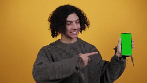 Young man holds smartphone with green screen showing swipe gesture to copy space Stock Footage 260783553