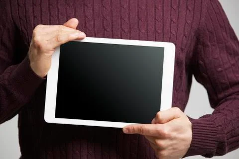 Young man holds a tablet computer showing its screen, mid section Fotos de archivo