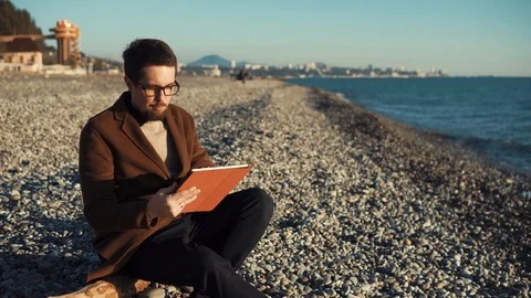 A young man holds a tablet in his hands and is engaged in online work Stock Footage 88596149