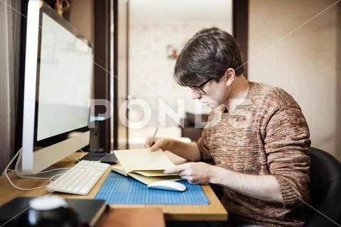 Young man at home using a computer, freelance developer or desig Stock Photos