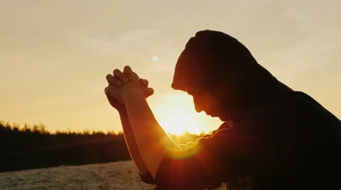 A young man in a hood sits at sunset, it is thoughtful, dreaming Stock Footage 66097752