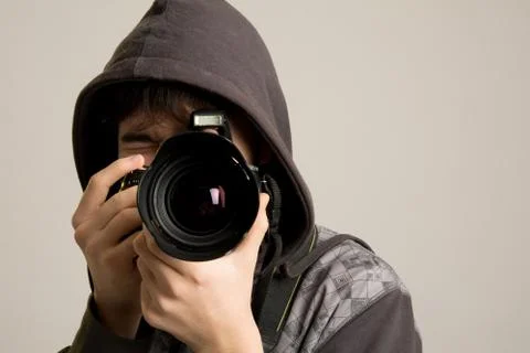 A young man in a hood using a professional camera Foto stock