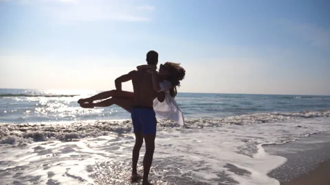 Young man hugging and spinning around his woman on sea beach. Lovers having fun Video stock 305705286