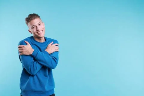 Young man hugging himself on light blue background, space for text Stock Photos