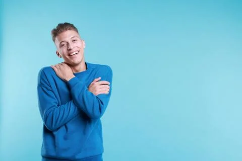 Young man hugging himself on light blue background, space for text Stock Photos
