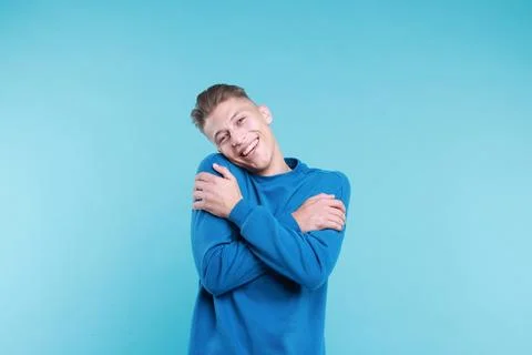 Young man hugging himself on light blue background Stock Photos