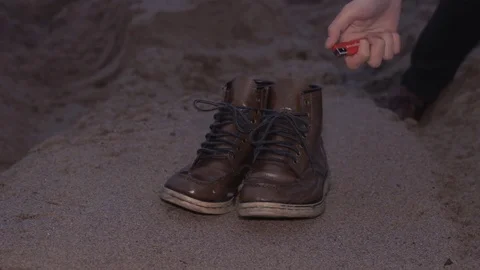 Young man Igniting shoes seating on the sand at coast Stock Footage 74378878
