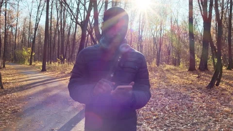 A young man, illuminated by the bright rays of the sun, stands in a beautiful Stock Footage 164145634