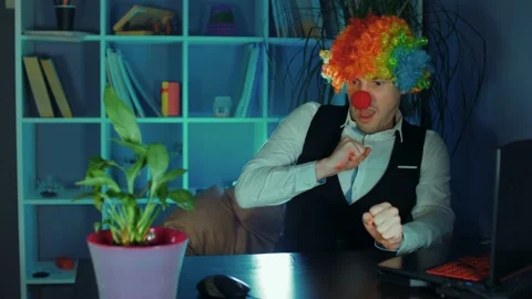 Young man in image of clown afraid of computer mouse in office. Funny clown sits Stock-Footage 160447964
