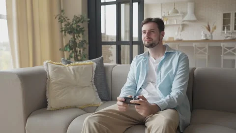 Young Man Immersed In Video Game Action While Sitting On Cozy Sofa At Home Stock Footage 304580891