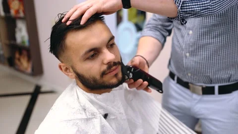 A young man impressed by the work of a barber smiles. He is very satisfied. The Stock Footage 143107911